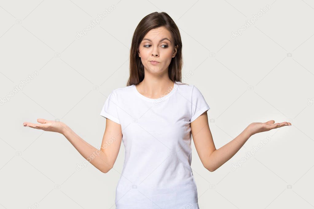 Millennial woman stretched hands thinking makes choice on grey background