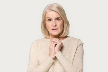 Endişeli kıdemli kadın birlikte gri arka planda izole eller katlanmış