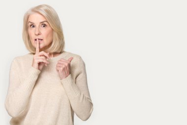Kıdemli kadın kopya boşluk kenara parmak işaret sus işareti yapar