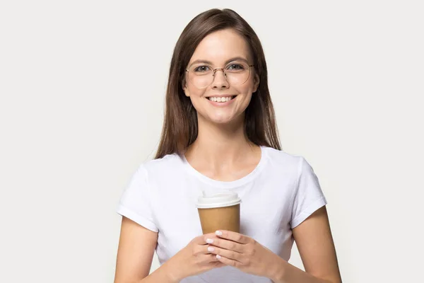 Привлекательная девушка, держащая чашку кофе, позирует на фоне серой студии — стоковое фото