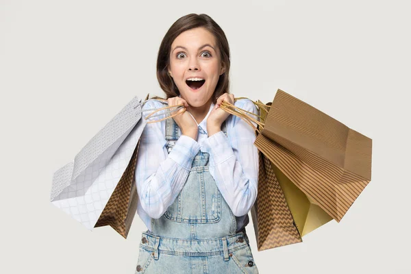 Shopper girl sosteniendo montones de bolsas aisladas en gris — Foto de Stock