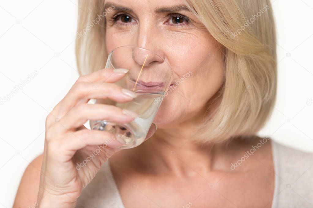 Close up aged attractive woman holding glass drinking water