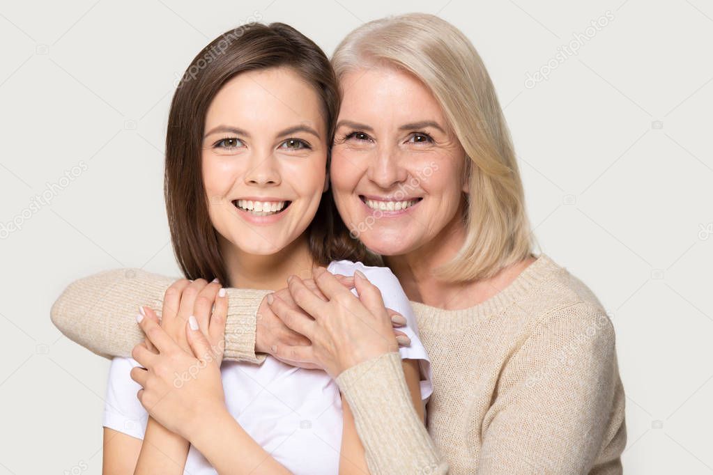 Headshot portrait attractive grandmother and granddaughter embracing looking at camera