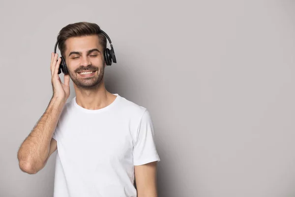 Guy usando fones de ouvido desfrutar de música favorita isolada em fundo cinza — Fotografia de Stock