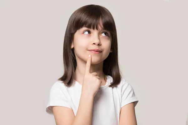 Pensive klein meisje greep vinger op de kin geïsoleerd op beige — Stockfoto
