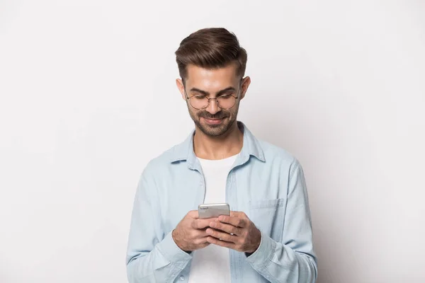 Positive guy in glasses using smart phone studio shot — Stock Photo, Image