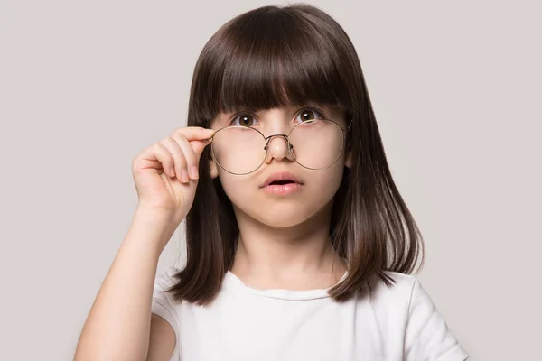 Funny klein meisje te verlagen glazen kijkend naar de camera voelen verbazing — Stockfoto