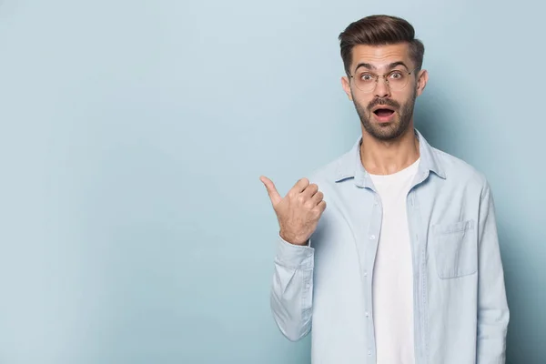 Surprised funny man wearing glasses pointing finger aside at copyspace — Stock Photo, Image