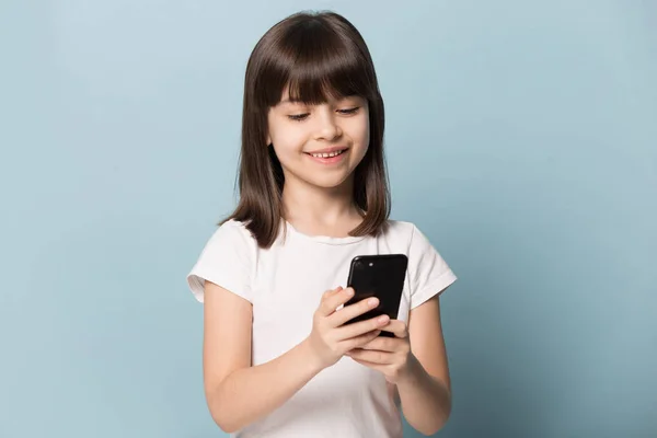 Little girl using smart phone posing isolated on blue background — Stock Photo, Image