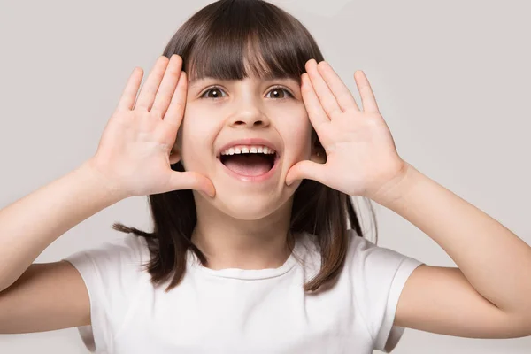 Mała dziewczynka nazywają kogoś trzymając ręce w pobliżu twarzy strzał studio — Zdjęcie stockowe