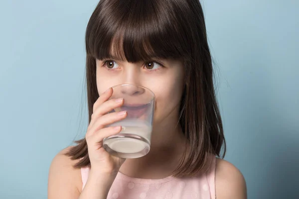 Closeup portrait little girl drinking milk studio shot on blue — Stock Photo, Image