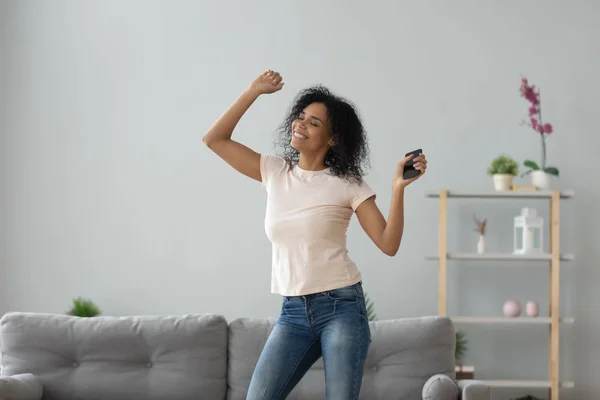 Senyum aktif wanita kulit hitam menari sendiri memegang telepon di rumah — Stok Foto