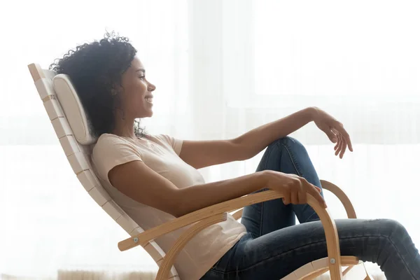 Happy calm african girl resting dreaming sit in rocking chair — Stock Photo, Image