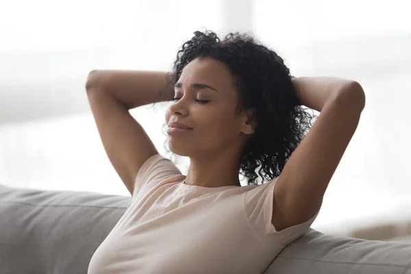 Relaxed happy african woman resting lounging sit on sofa — Stock Photo, Image