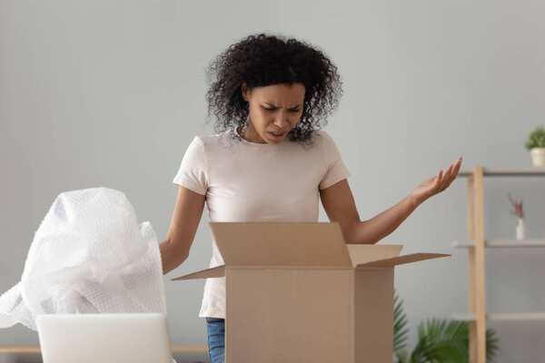 Disappointed shocked african woman open cardboard box receive bad parcel