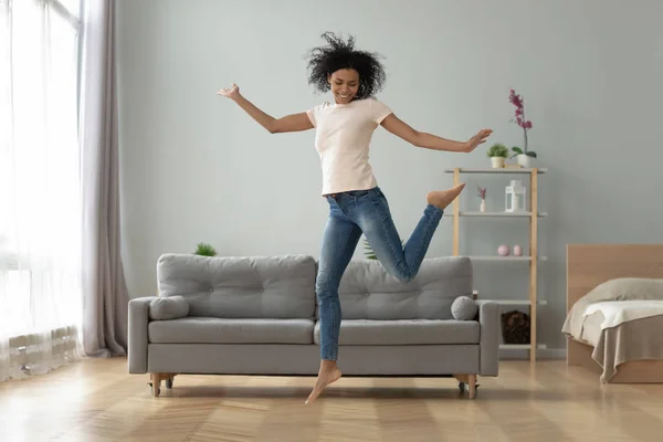 Zorgeloos vrolijk Afrikaans meisje springen dansen alleen thuis — Stockfoto