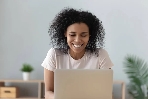 Cheerful african girl laughing watching funny online show on laptop — Stock Photo, Image