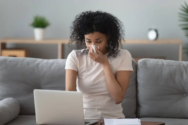 Allergische Afrikaanse vrouw waait neus in servet zitten thuis — Stockfoto