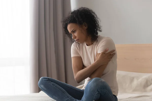 Upset depressed african woman feel sad sit alone on bed — Stock Photo, Image