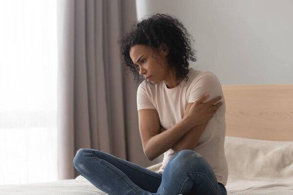 Расстроенная депрессия африканская женщина чувствовать себя грустно сидеть в одиночестве на кровати
