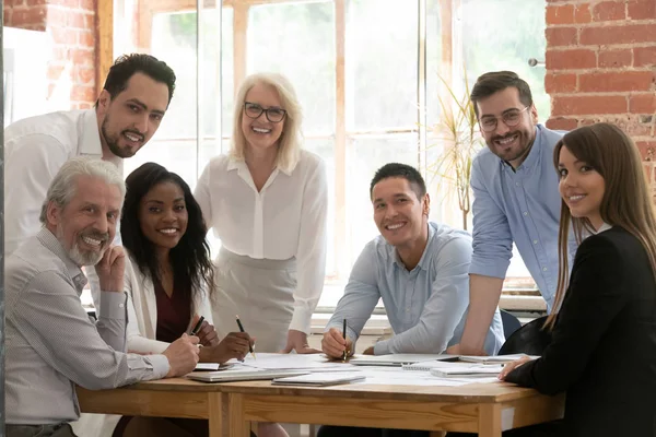 Team di lavoro professionale giovani e anziani in posa a tavola — Foto Stock