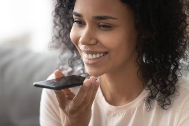 Gülümseyen Afrikalı kadın akıllı telefonda sanal dijital ses asistanı etkinleştirmek