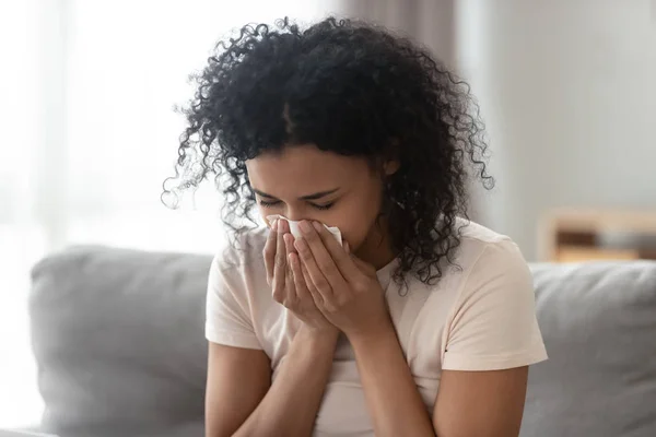 Malade femme africaine allergique qui se mouche dans les tissus à la maison — Photo