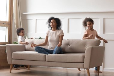 Sakin afrikalı anne çocuklarla rahatlatıcı kanepede yoga yapıyor