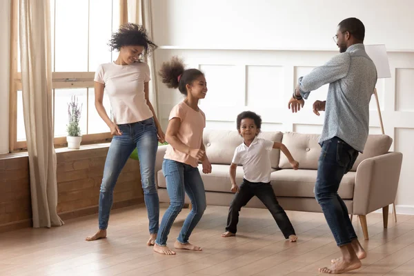 Happy funny active african family of four dancing at home — Stock Photo, Image