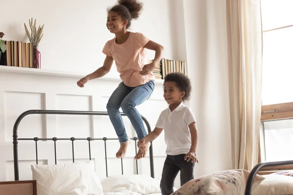 Mutlu küçük afrikalı çocuk erkek ve kız yatakta atlama — Stok fotoğraf