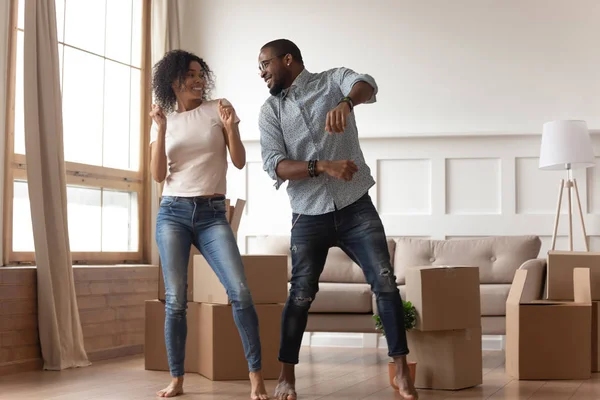 Feliz pareja africana bailando riendo en la sala de estar con cajas — Foto de Stock