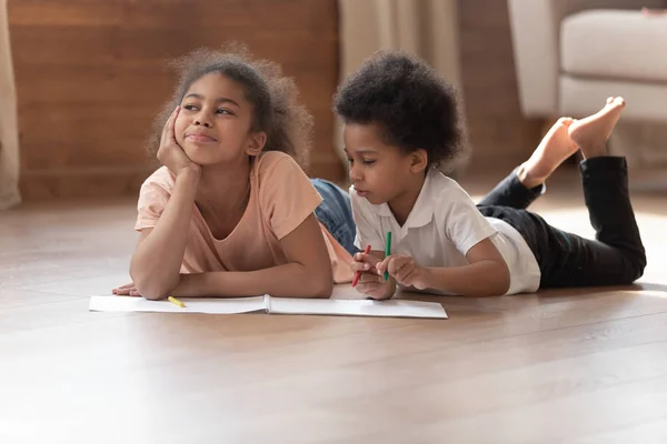 Twee leuke Afrikaanse kinderen spelen tekenen samen op warme vloer — Stockfoto