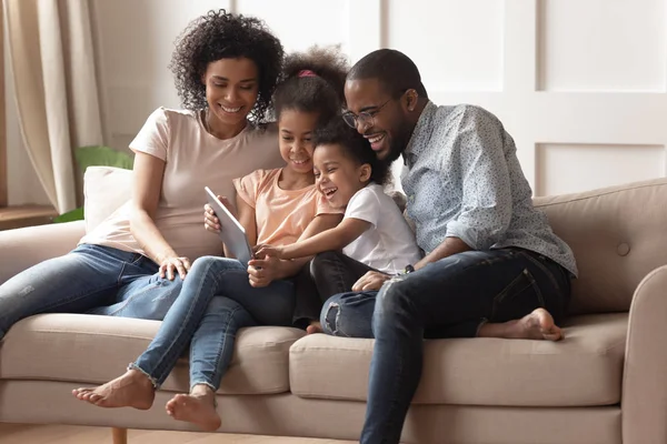 Happy black parents and children using digital tablet on sofa — Stock Photo, Image