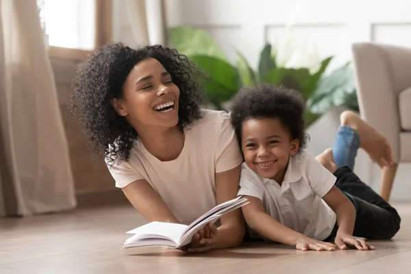 Afrikaanse moeder lezen boek lachen met kind zoon thuis — Stockfoto