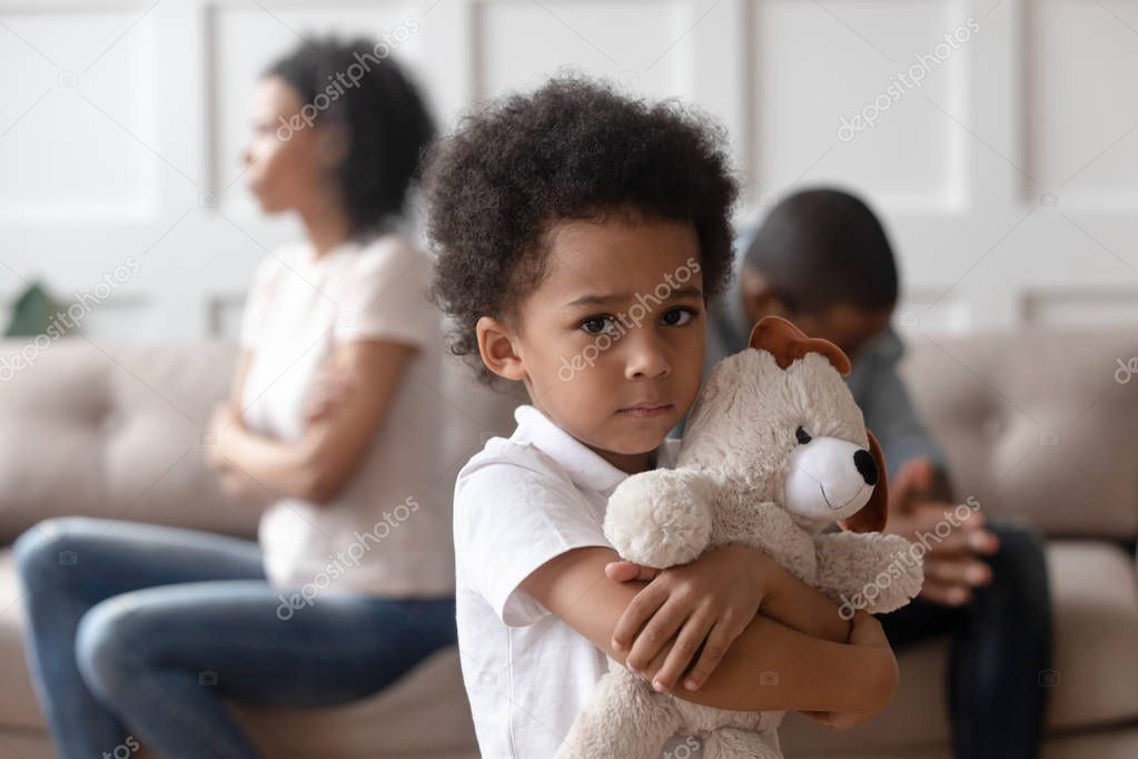Upset little african child boy holding toy looking at camera