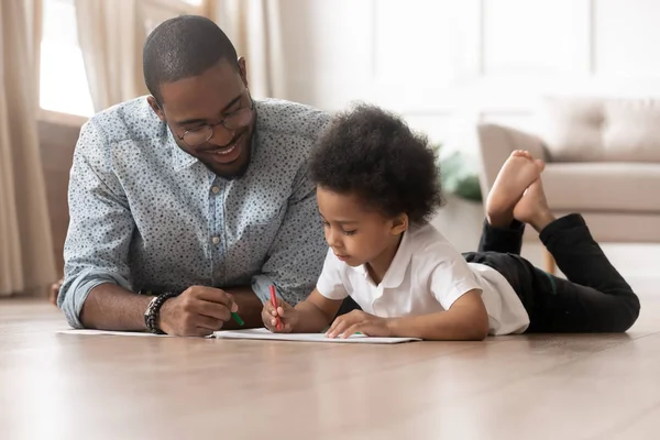 Happy family african dad and cute kid boy drawing together