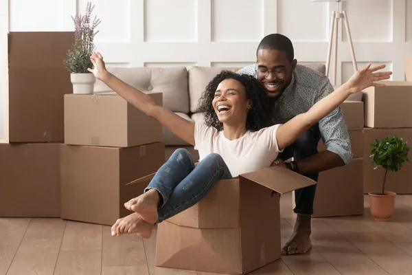 Happy african young couple riding in box on moving day — Stock Photo, Image