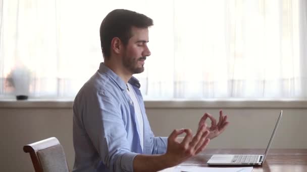 Ruhiger, achtsamer junger Mann macht Pause und sitzt meditierend am Schreibtisch — Stockvideo