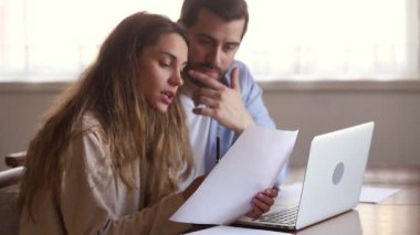 Ciddi çift dizüstü bilgisayar ile oturan iç faturaları okuma kağıtları tutan