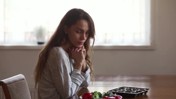 Tvivelaktig olycklig ung kvinna väljer mellan sallad och godis — Stockvideo