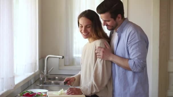 Счастливая любящая молодая пара весело готовит здоровую еду вместе — стоковое видео