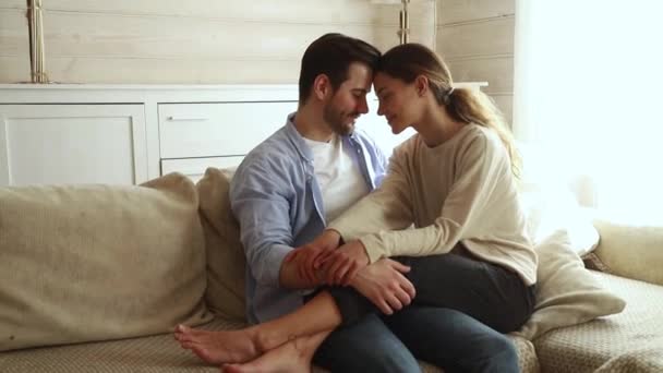 Romantikus boldog fiatal pár megható homlokukon nevetve hozzábújva a kanapén — Stock videók