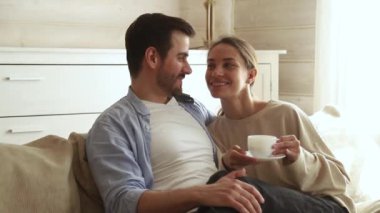 Mutlu çift kanepede oturan kahve çayı içme konuşurken kucaklayan