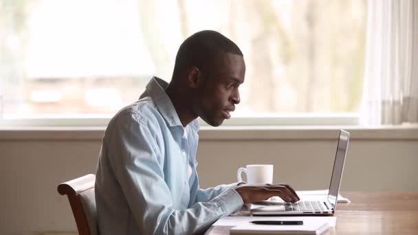 Boldog afrikai fiatalember olvasó nagy hírek online használ laptop — Stock videók