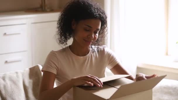 Gelukkige Afrikaanse vrouw klant ontvangen kartonnen doos open geleverd pakket — Stockvideo