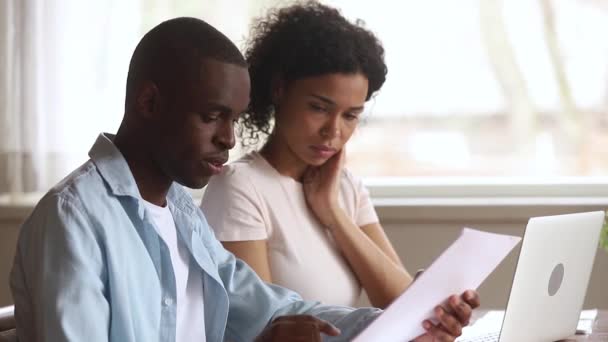 Grave pareja afroamericana haciendo papeleo uso de la computadora portátil juntos — Vídeo de stock