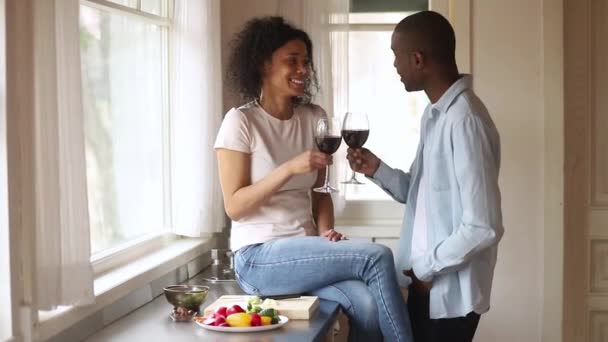 Feliz africano pareja tintineo gafas hablar risa vinculación en cocina — Vídeo de stock