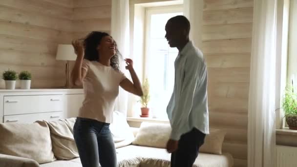 Щаслива фанк молода африканська пара танцює стрибки у вітальні — стокове відео
