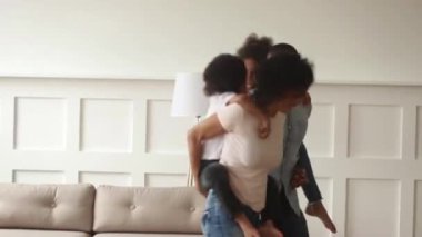 Siyah anne evde oynayan çocuklar taşıyan piggyback binmek vermek