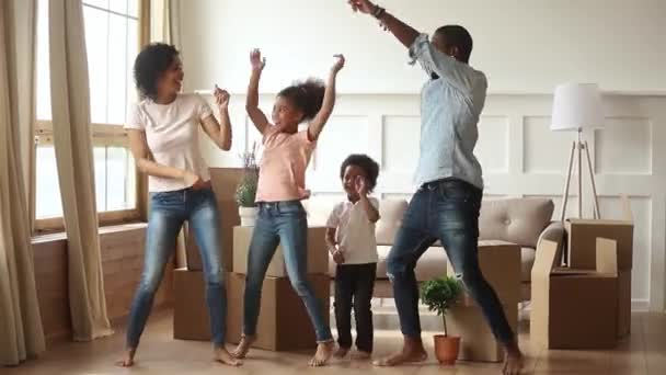 Счастливые родители африканской семьи и дети танцуют, отмечая день переезда — стоковое видео